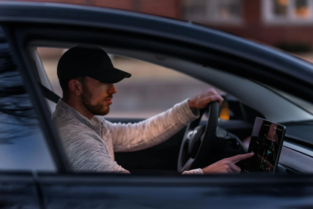 Man in Gray Long Sleeve Shirt Driving a Tesla Car